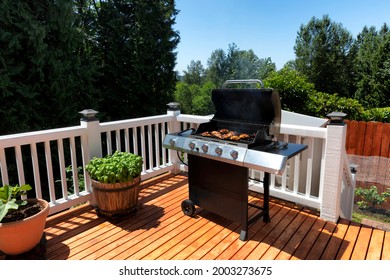 Close Up Of An BBQ Cooker With Lid Open Displaying Smoke Coming Out While On Home Outdoor Wooden Deck During Summertime 