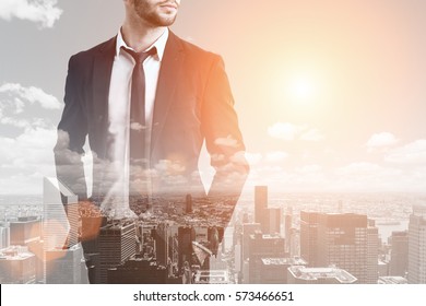 Close up of a bearded businessman standing with his hands in pockets against a morning city panorama. Mock up. Toned image. Double exposure