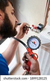 Close Up Of Bearded Man Filling Pipes With Pressurized Air To Inspect For Leaks In New Installation. Worker Using Manometer, Checking Gas Tightness Of Heating System. Concept Of Gas Tightness Testing.