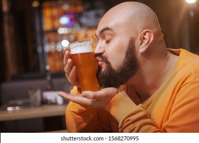 Close up of a bearded man kissing glass of delicious beer at the pub
