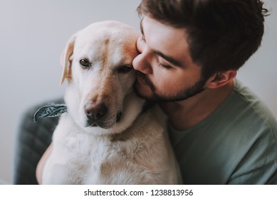 Close up of a bearded man kissing his dog while enjoying rest together