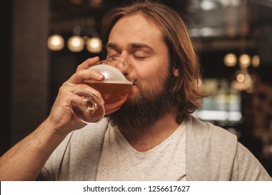 Close up of a bearded man sipping delicious craft beer with his eyes closed, resting at the bar. Happy relaxed male customer drinking beer, celebrating holidays at the pub. Oktoberfest, relax concept - Powered by Shutterstock