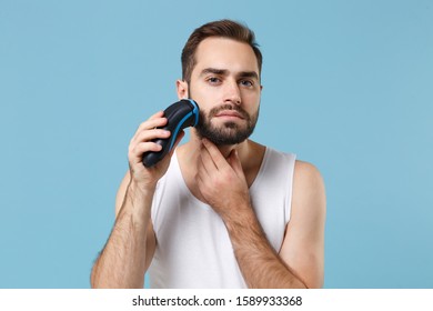 Close up bearded young man 20s years old in white shirt hold electric razor isolated on blue pastel background, studio portrait. Skin care healthcare cosmetic procedures concept. Mock up copy space - Shutterstock ID 1589933368