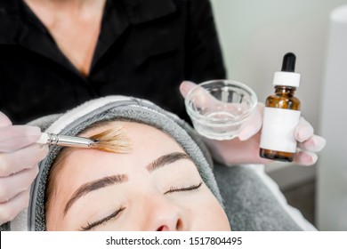 Close up of beautician (cosmetologist) applying chemical peel treatment on patient in a beauty spa, for skin rejuvenation, complexion and acne beauty treatments.