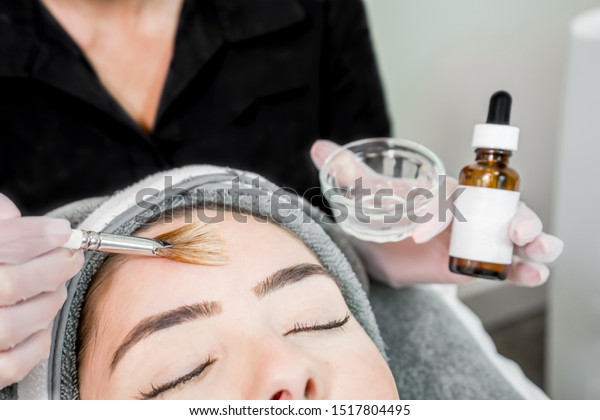 Close up of beautician\
(cosmetologist) applying chemical peel treatment on patient in a\
beauty spa, for skin rejuvenation, complexion and acne beauty\
treatments.