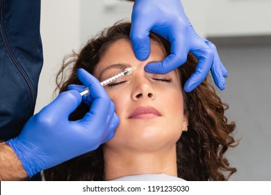 Close up of beautician expert's hands injecting botox in female forehead. - Powered by Shutterstock