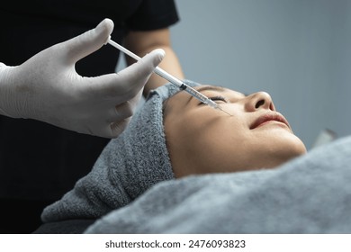 Close up beautician wearing hygiene gloves injecting filler on woman cheek for facial treatment to female Asian client in beauty clinic - Powered by Shutterstock