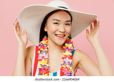 Close Up Beautiful Attractive Happy Young Woman Of Asian Ethnicity Wear Swimsuit Hawaii Lei White Hat Look Camera Isolated On Plain Pastel Pink Background. Summer Vacation Sea Rest Sun Tan Concept.