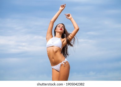 Close up beautiful brunette sexy woman in white bikini on blue sky background