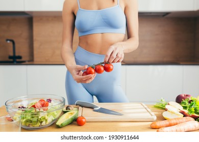 close up beautiful female athlete preparing a salad of vegetables, a woman has a perfect athletic body, doing fitness at home