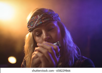 Close up of beautiful female musician playing harmonica in nightclub - Powered by Shutterstock