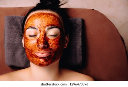 Close up of a beautiful female resting with close eyes with a chocolate mask on her face. Spa procedures with chocolate .