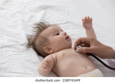 Close Up Beautiful Infant Boy Or Girl In Diaper, Cute Newborn Baby Lying On White Bedsheet Looks At Doctor Therapist Use Stethoscope Make Heart Rate Checkup, Examining Heartbeat. Paediatrics Concept