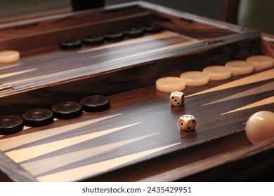 Close up of beautiful inlaid wood backgammon board set up and ready to play with first play white dice rolled