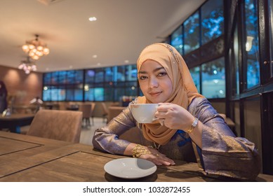 Close up of beautiful muslim woman sit and drinking hot coffee in cafe.