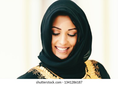 Close Up Of Beautiful Muslim Woman With Toothy Smile Looking Down.