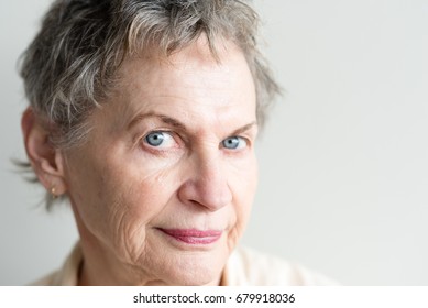 Close Up Of Beautiful Older Woman With Short Grey Hair And Blue Eyes Raising Eyebrow And Looking Skeptical (selective Focus)