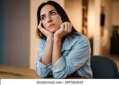 Close up of a beautiful pensive young woman thinking while sitting indoors