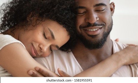 Close up beautiful serene african couple embracing closed eyes enjoy tender moment of unity and tenderness, enamored woman and man sharing lives and days, endearment and fidelity, forever love concept