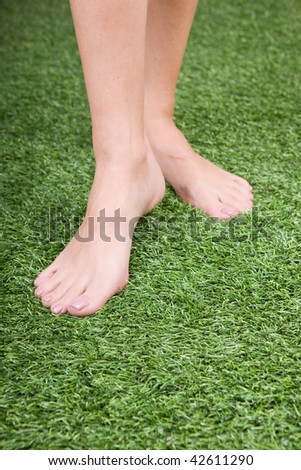 Close up of beautiful slim female feet on green grass