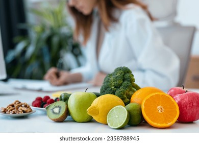 Close up of beautiful smart nutritionist woman working with computer while taking notes in the nutritionist consultation