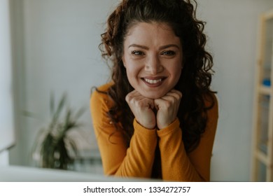 Close up of a beautiful smiling curly brunette looking at camera, hands on chin. - Shutterstock ID 1334272757
