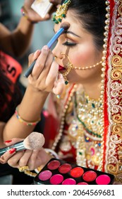 Close Up Of The Beautiful Traditional Indian Bride Getting Ready For Her Wedding Day. Cropped Hand Of Makeup Artist Doing A Makeup Of Bridal Face And Applying Lipstick.