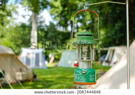Close up Beautiful vintage camping lantern hanging on a steelstand with a background of tents in the camping,Relaxing in the midst of nature
