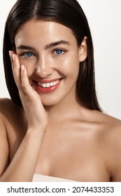 Close Up Of Beautiful Woman With Clean, Nourished Facial Skin, Touching Her Face Without Makeup And Smiling From Satisfaction, Soft And Healthy Skin Condition, White Background