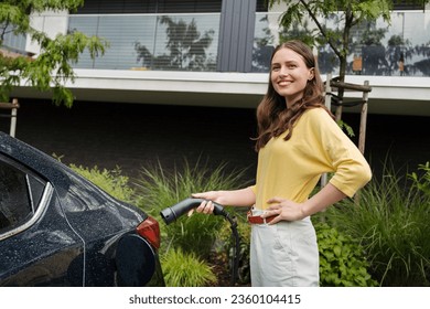 Close up of beautiful woman plugging charger in her electric car. Progressive woman charging her electric car on the street. - Powered by Shutterstock