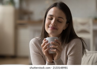Close up beautiful woman relaxing on sofa with eyes closed, hold tea cup, take break at home enjoy favourite beverage looks carefree, relish aroma of coffee, daydreams alone indoor. No stress concept - Shutterstock ID 2133148981