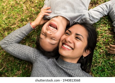 Close up beautiful woman tickling her daughter have fun relax on the grass outdoor.