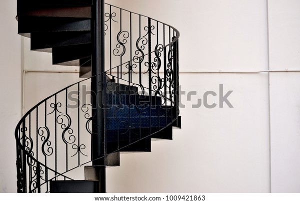 Close up of beautiful wrought iron exterior\
spiral staircase on the side of a shop house in Singapore with copy\
space for design\
