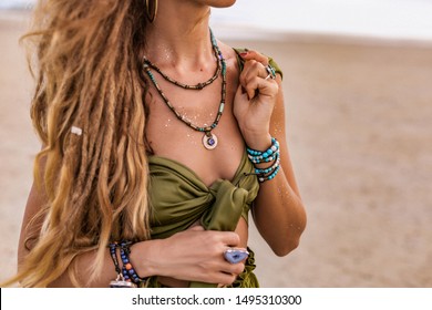 close up of beautiful young stylish woman walking on the beach at sunset