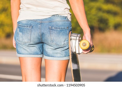 Close Up Of Beautiful Young Woman Holding Skateboard Deck In Hands, Back View