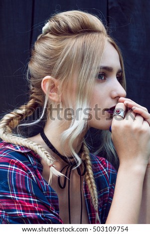 Close up of beautiful young woman with strong dark makeup and purple lips. Professional modern stylish fashionable hairstyle. Created from small and large braids and loose hair.
