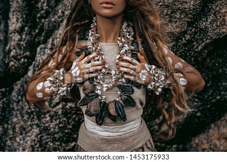 close up of beautiful young woman in tribal costume with primal ornamet on skin and lot of tribal accessories and jewelry