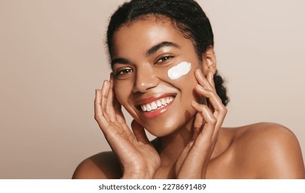 Close up beauty girl with thick eyebrows, applying moisturizing skincare cream, lotion or mask for skin lifting and anti-aging detoxifying effect, beige background. Copy space - Powered by Shutterstock