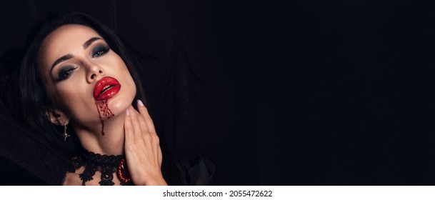 Nahaufnahme der Schönheit halloween Porträt einer schönen jungen Frau als sexy Vampire mit Blut auf schwarzem Hintergrund, Banner mit Kopienraum für Text