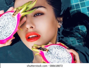 Close Up  Beauty Portrait Of Beautiful Woman With Slice Of Dragon Fruit,  Bright Make Up. Sensual Model With Perfect Skin And Full Lips  Holding Tropical Fruits  In Pool. 