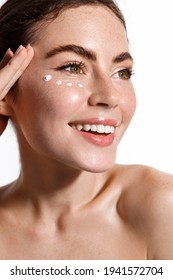 Close Up Beauty Portrait Of Girl Freckles, Nude Naked Skin, Applying Facial Cream Under Eye For Anti Aging, Detox And Lifting Effect, Treating Fresh Clean Face, White Background.