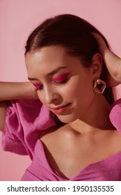 Close up beauty portrait of young beautiful woman with pink, fuchsia color eyeshadow makeup, flawless clean skin, wearing elegant golden earrings, pink blouse. Spring, summer fashion trend - Shutterstock ID 1950135535