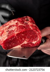 Close up beef meat in chef butcher's hands with knife on black background - Shutterstock ID 2123723756