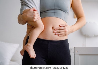 Close up of a belly with scar from c-section. A woman holding a baby showing her imperfect body. An abdomen with scar from Caesarian section. - Shutterstock ID 2139154233