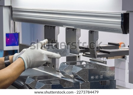 Close up the bending machine operator hold the sheet metal parts and  wear the rubber glove. The sheet metal working operation by skill operator.