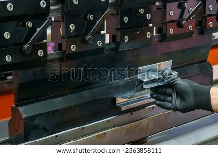 Close up the bending machine operator hold the sheet metal parts and  wear safety  rubber glove. The sheet metal working operation by skill operator.