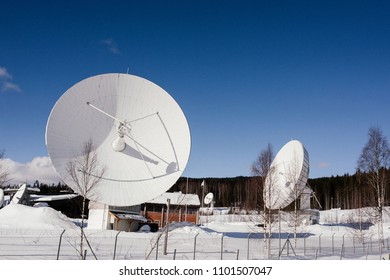 Close up big satellite dishes or radio antennas in radio observatory near the forest in Norway in winter. Blue sky