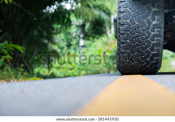 close\
up big tire on asphalt road on summer day at\
park