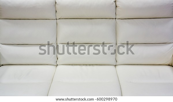 close up of big white lather soft sofa divided into\
three vertical sections for comfortable waiting on reception or in\
waiting room in big office. close up of white sofa in a waiting\
room