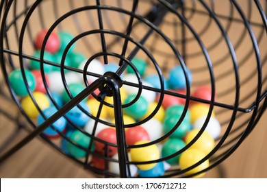 A Close Up Of A Bingo Cage Filled With Multi-colored Balls. Each Ball Has A Letter And Number On It That Corresponds To A Number On The Player's Bingo Card. Bingo Is A Game Of Chance.